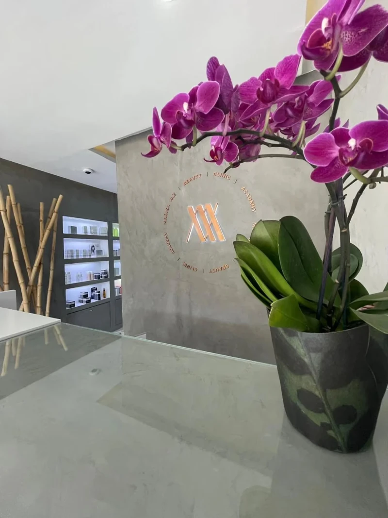 Receção da clínica Marisa Vaz, com o símbolo da marca na parede e uma orquídea em primeiro plano.